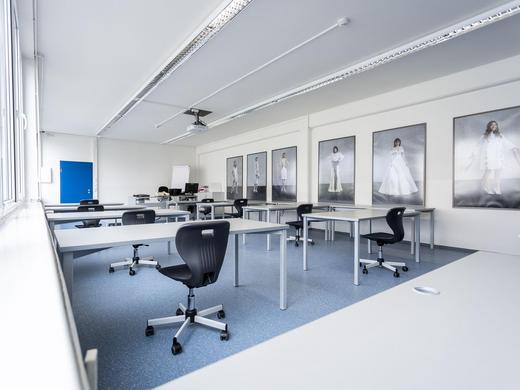 Moderner Unterrichtsraum mit weißen Tischen und Grauen Bürostühlen im Hauptgebäude Laiz