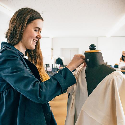 junge Frau drapiert Stoff an der Schneiderbüste