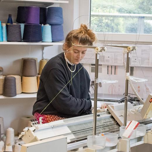 Schülerin sitzt an der Strickmaschine