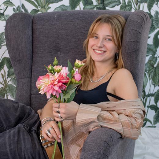 Schülerin sitzt auf dem Sessel mit Blumenstrauß