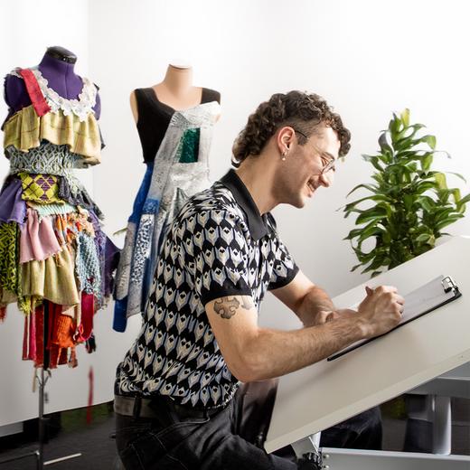 junger Mann sitzt am Zeichentisch und zeichnet