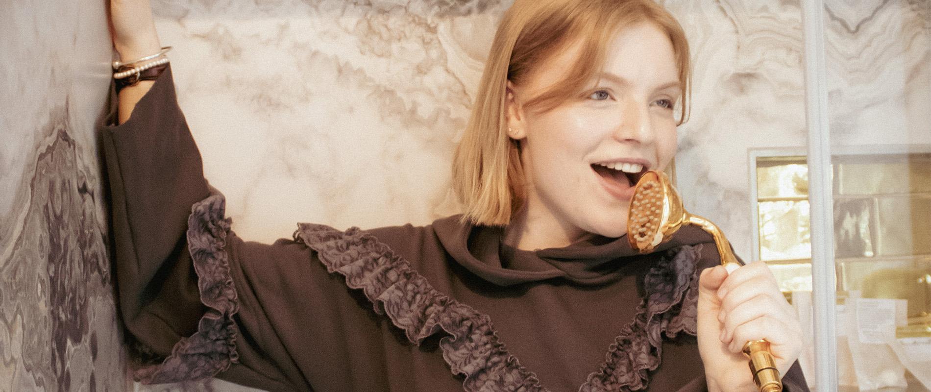 junge Frau telefoniert mit Duschkopf