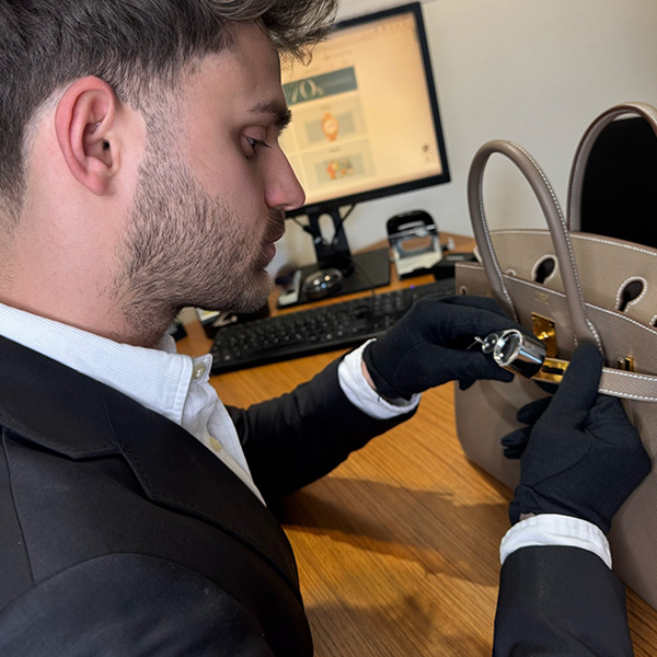 junger Mann bei der Qualitätskontrolle einer Designertasche