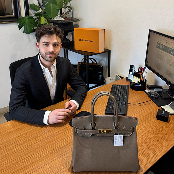 junger Mann mit Designertasche auf dem Tisch