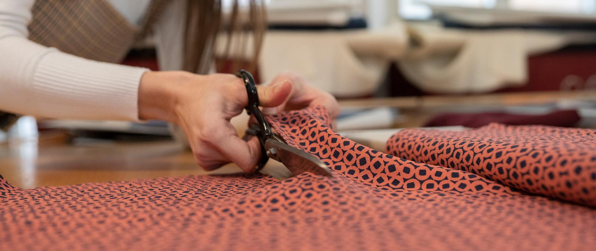 Frauenhände beim Stoff zuschneiden 